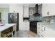 Well-lit kitchen features stainless appliances, white cabinets, mosaic tile backsplash, and a marble countertop island at 13204 Kakapo Ave, Port Charlotte, FL 33981