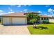 Charming home with a three-car garage, a paved driveway, and well-manicured lawn and tropical landscaping at 13830 Begonia Cir, Port Charlotte, FL 33981