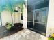 Inviting entryway featuring a screened-in porch, a paved walkway, and tropical plants at 13830 Begonia Cir, Port Charlotte, FL 33981