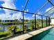 Relaxing pool with a screened enclosure boasting scenic canal views with lush palm trees and landscaping at 13830 Begonia Cir, Port Charlotte, FL 33981