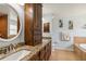 Bathroom featuring wood cabinetry, granite countertops, a round mirror, and a large soaking tub at 15104 Aldama Cir, Port Charlotte, FL 33981