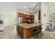 Open-concept kitchen features stainless steel appliances, wood floors, granite counters, and breakfast bar at 15104 Aldama Cir, Port Charlotte, FL 33981