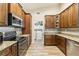 Well-lit kitchen features wood floors, stainless steel appliances, granite counters, and access to a laundry room at 15104 Aldama Cir, Port Charlotte, FL 33981