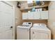 Laundry room with washer, dryer, white cabinets and shelving above at 15104 Aldama Cir, Port Charlotte, FL 33981