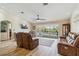 Spacious living room features tile floors, a ceiling fan, a sliding glass door with a view of the pool at 15104 Aldama Cir, Port Charlotte, FL 33981
