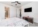 Bedroom featuring ensuite bathroom, ceiling fan, large tv, and floral patterned bedding at 16965 Hawk Ct, Punta Gorda, FL 33982