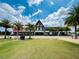 Exterior shot of a community building with palm trees, a vibrant lawn, and architectural details under a sunny sky at 16965 Hawk Ct, Punta Gorda, FL 33982