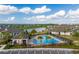 Aerial view of a community pool featuring lounge chairs, palm trees and clubhouse overlooking a tranquil lake at 16965 Hawk Ct, Punta Gorda, FL 33982