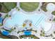 Aerial view showcasing a large community pool with sunbeds and umbrellas surrounded by palm trees and landscaping at 17557 Santorini Ct, Venice, FL 34293