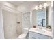 Well-lit bathroom featuring a neutral color palette, tiled shower, and modern vanity with a decorative cabinet above the toilet at 17557 Santorini Ct, Venice, FL 34293