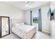 Bright bedroom with a ceiling fan, a large window, and a wall-mounted TV, blending comfort and modern amenities at 17557 Santorini Ct, Venice, FL 34293
