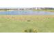 Golf driving range with manicured grass, water hazard, and golfer practicing their swing at 17557 Santorini Ct, Venice, FL 34293