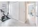 Neutral-toned exercise room, showcasing a Peloton bike and offering a view into another brighter room at 17557 Santorini Ct, Venice, FL 34293