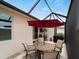 A cozy screened patio features an outdoor dining set and a red umbrella for shade at 17857 Woodland Ct, Punta Gorda, FL 33982