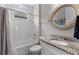 Bathroom with tiled tub and shower, granite vanity, and round mirror at 19821 Montenero Way, Venice, FL 34293