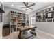 Home office with built-in shelving, ceiling fan, and a wooden desk at 19821 Montenero Way, Venice, FL 34293