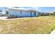 Single-story home showcases light blue siding, a well-manicured lawn, and charming landscaping near the entrance at 22299 Laramore Ave, Port Charlotte, FL 33952