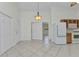 Open-concept kitchen with white appliances, wooden cabinets, and tile flooring with lots of entryways at 22299 Laramore Ave, Port Charlotte, FL 33952