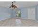 Open-concept living room featuring tile flooring, a ceiling fan, a front door, and a shuttered window at 22299 Laramore Ave, Port Charlotte, FL 33952