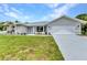 Charming single-story home showcasing a manicured front lawn, complemented by a paved driveway at 229 Waterside St, Port Charlotte, FL 33954