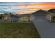 Beautiful one-story home with an attached two car garage, lush green lawn, and a colorful sunset at 229 Waterside St, Port Charlotte, FL 33954