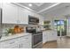 Bright kitchen features white cabinets, stainless steel appliances, and a view to the screened-in patio at 229 Waterside St, Port Charlotte, FL 33954