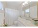 Bright bathroom showcasing a tub with curtain, vanity with sink, and a large vanity mirror at 23165 Glen Ave, Punta Gorda, FL 33980