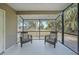 Screened patio featuring two chairs and a view of a well-maintained lawn and tropical landscaping at 23165 Glen Ave, Punta Gorda, FL 33980