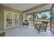 Screened patio featuring two chairs and a view of a well-maintained lawn and tropical landscaping at 23165 Glen Ave, Punta Gorda, FL 33980