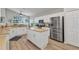 Open kitchen with white cabinets, stainless steel appliances, island and breakfast bar at 24358 Folkstone Ave, Punta Gorda, FL 33980