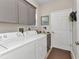 Functional laundry room features front load washer and dryer, upper cabinets, and counter space at 24358 Folkstone Ave, Punta Gorda, FL 33980