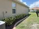 View of side yard, showing green grass and a concrete edging along the back of the home at 25008 Lalique Pl, Punta Gorda, FL 33950