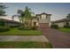 Well-maintained two-story home with lush landscaping and a brick driveway, creating a welcoming curb appeal at 2515 Sherman Oak Dr, North Port, FL 34289
