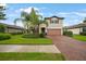 Charming two-story home featuring well-manicured lawn, mature palm trees, and a brick paved driveway at 2515 Sherman Oak Dr, North Port, FL 34289