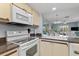Close-up of a kitchen with white appliances and a view into the dining and living spaces at 25275 Rampart Blvd # 1504, Punta Gorda, FL 33983