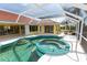Backyard view of the screened-in pool and spa with an outdoor dining area at 3506 Saint Florent Ct, Punta Gorda, FL 33950