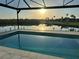 Relaxing pool overlooking a serene lake at sunset, surrounded by lush greenery and palm trees at 3548 Mondovi Ct, Punta Gorda, FL 33950