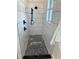 Modern shower with black fixtures, pebble flooring, and textured white tiled walls at 3548 Mondovi Ct, Punta Gorda, FL 33950