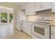 Well-lit kitchen featuring white appliances and cabinets, complemented by tile flooring at 4346 Rayfield Dr # 4346, Sarasota, FL 34243