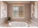 Close-up of the soaking tub in a bathroom with neutral colors, tiled surround and plantation shutters at 523 Saint Girons Ct, Punta Gorda, FL 33950