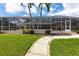 View of the screened pool enclosure and landscaped yard with mature palm trees at 523 Saint Girons Ct, Punta Gorda, FL 33950