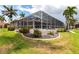 A screened pool enclosure is surrounded by lush landscaping and tropical palm trees at 523 Saint Girons Ct, Punta Gorda, FL 33950