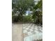Outdoor checkered tile area, surrounded by lush greenery, creating a private retreat in the backyard at 5727 Beechwood St, Punta Gorda, FL 33982