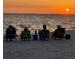 A serene beach scene with people relaxing in chairs at sunset, creating a peaceful and inviting atmosphere at 5727 Beechwood St, Punta Gorda, FL 33982