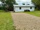 A well-maintained white home with a gravel driveway and lush green lawn providing ample outdoor space at 5727 Beechwood St, Punta Gorda, FL 33982