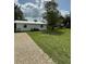 A single-story home featuring a gravel driveway, set against a backdrop of a large grassy lot and mature trees at 5727 Beechwood St, Punta Gorda, FL 33982