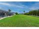 Expansive backyard with lush green grass, mature palms, and a screened lanai with a pool at 7512 Pon Kan, Punta Gorda, FL 33955