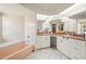 Traditional bathroom featuring a soaking tub, white cabinetry, dual sinks, and a mirrored wall at 891 Bayard St, Port Charlotte, FL 33948