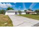 Exterior view of home featuring driveway, two-car garage, and tropical landscaping in the front yard at 891 Bayard St, Port Charlotte, FL 33948