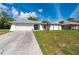 Charming single-story home featuring a two-car garage, and tropical landscaping in a well-maintained lawn at 891 Bayard St, Port Charlotte, FL 33948